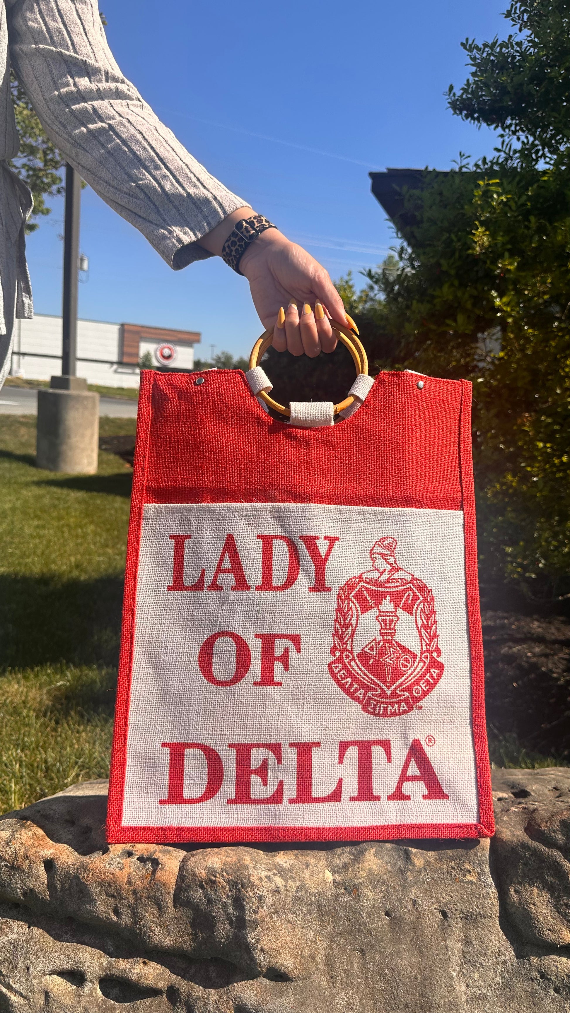 Red and white bag with 'Lady of Delta' text held by a person outdoors.